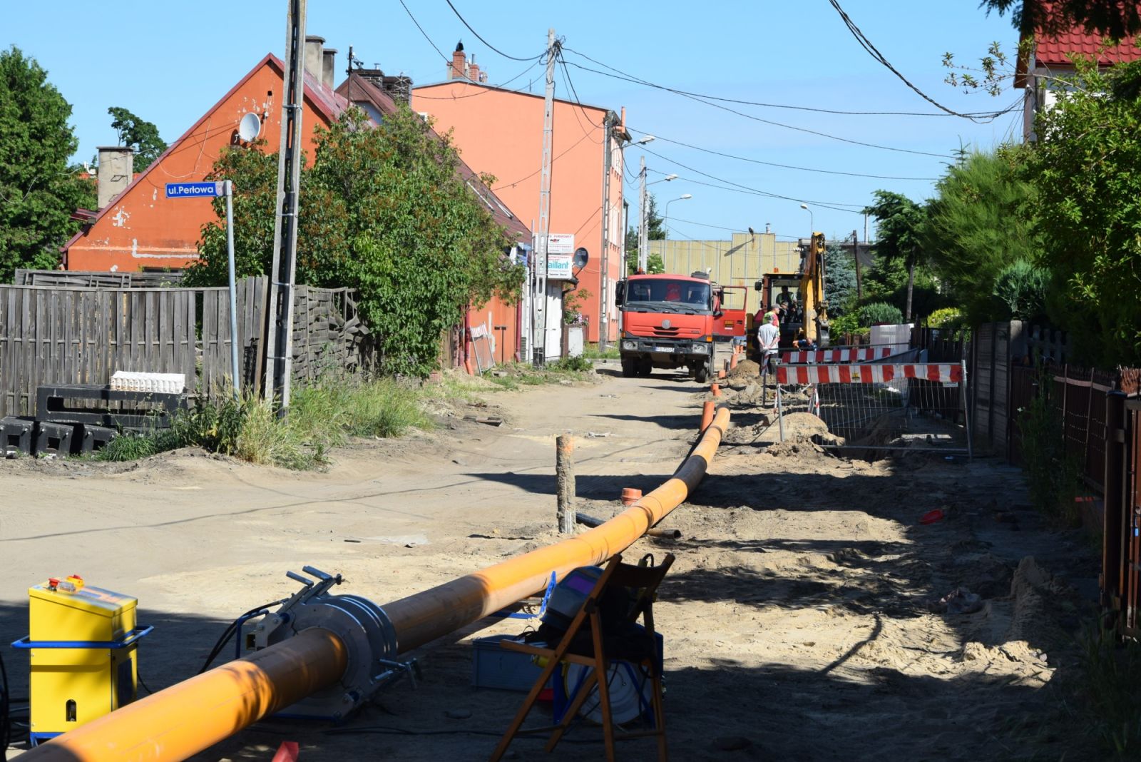 Powiększ zdjęcie. Rura gazowa lezy na drodze w oddali samochód ciężarowy i koparka
