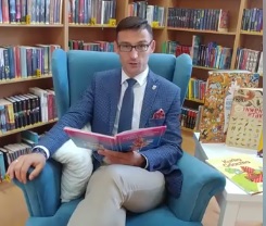 Burmistrz Dębna siedząc w fotelu czyta książkę 