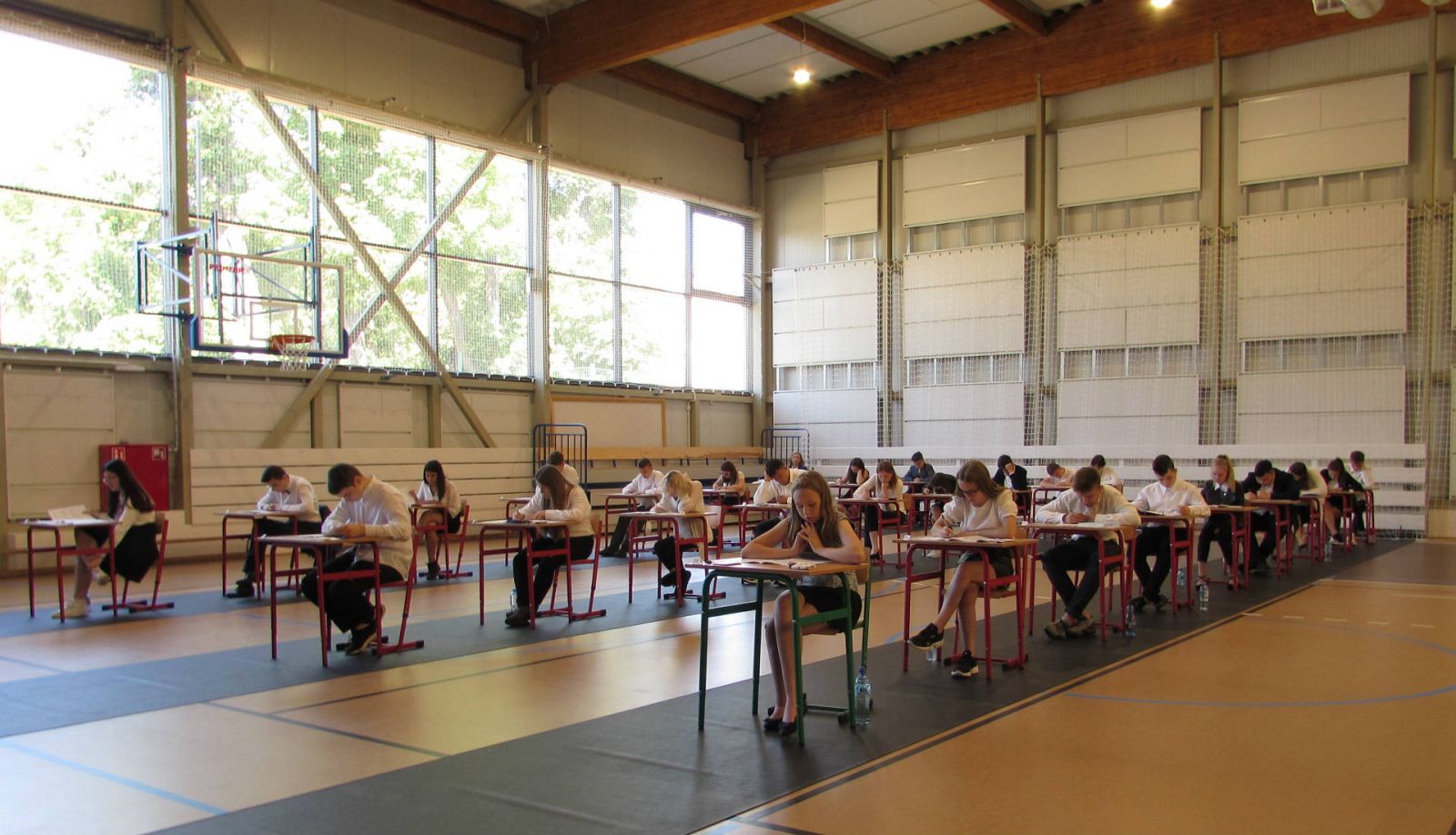 Powiększ zdjęcie. Uczniwiez SP3 na hali siedzą w ławkach
