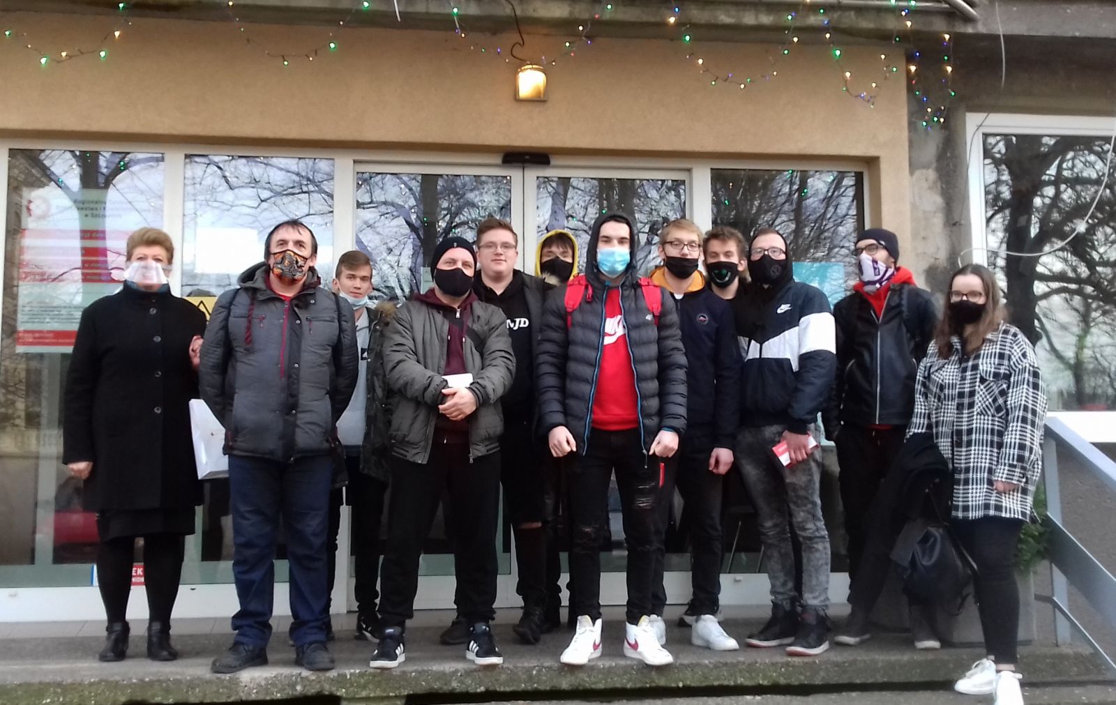 Powiększ zdjęcie. Grupa młodzieży wraz z opiekunem stoi przed wejściem do Centrum Krwiodawstwa
