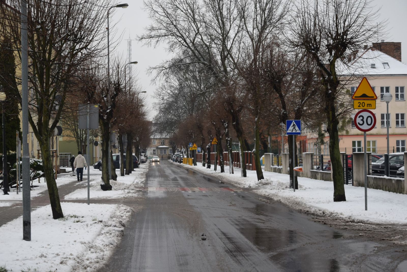 Powiększ zdjęcie. Droga gminna, śnieg na chodnikach, drzewa