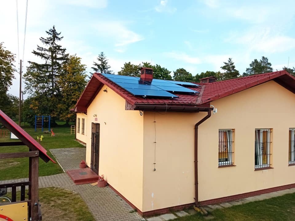 Panele na dachu świetlicy, niebo, drzewa