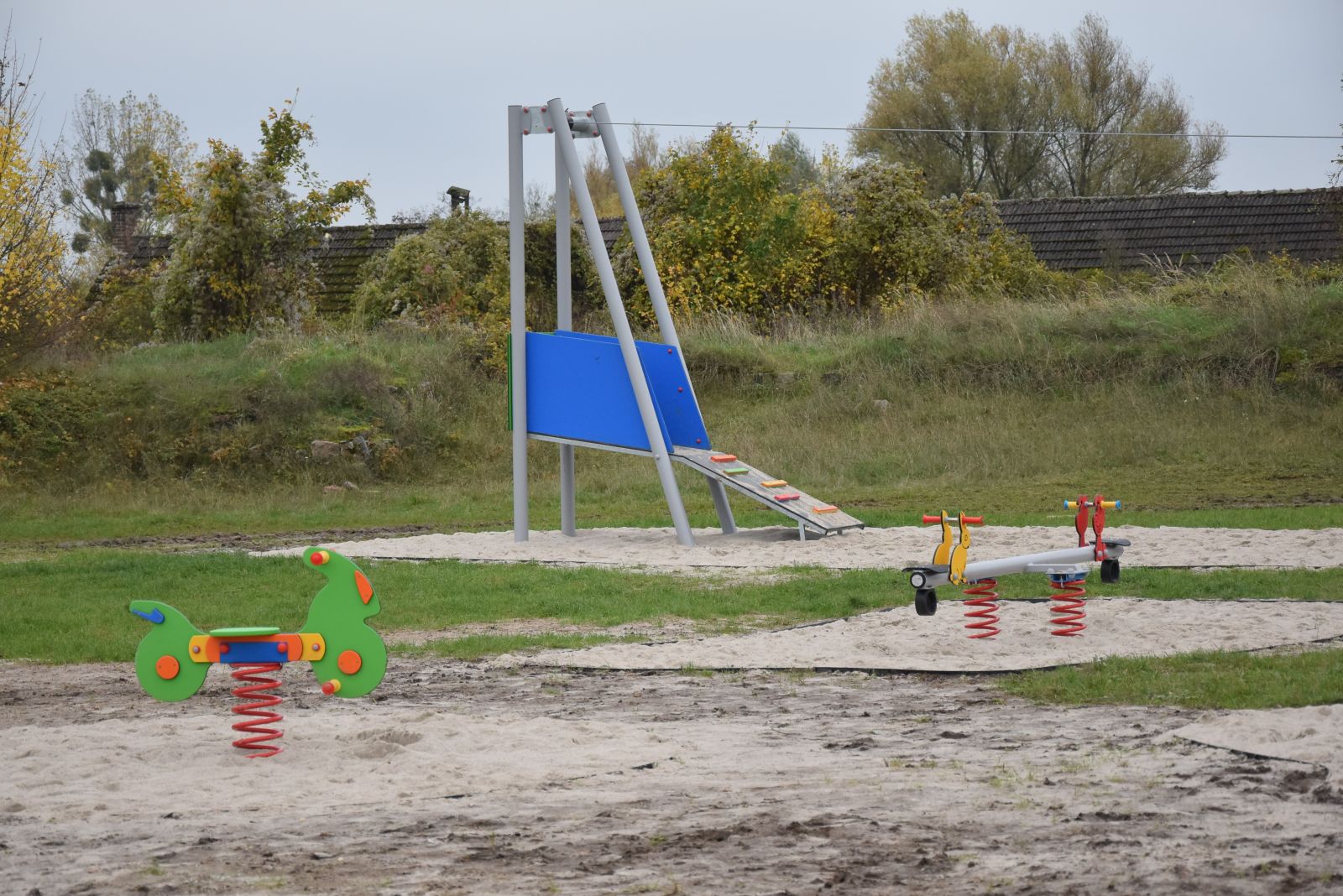 Powiększ zdjęcie.  Zabawki bujaki na sprężynie, platforma zjazdu linowego, krzaki, niebo