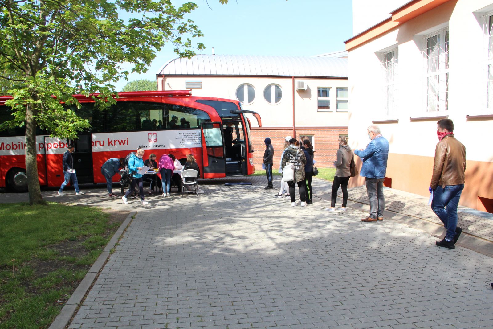 Powiększ zdjęcie. Ludzie stoją w kolejce do ambulansu