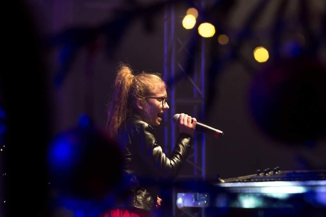 Powiększ zdjęcie. Wiktoria Taracińska z mikrofonem w ręku.