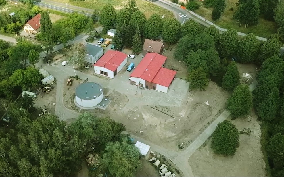 Powiększ zdjęcie z lotu ptaka. Widoczna cała stacja z góry, budynki, drzewa