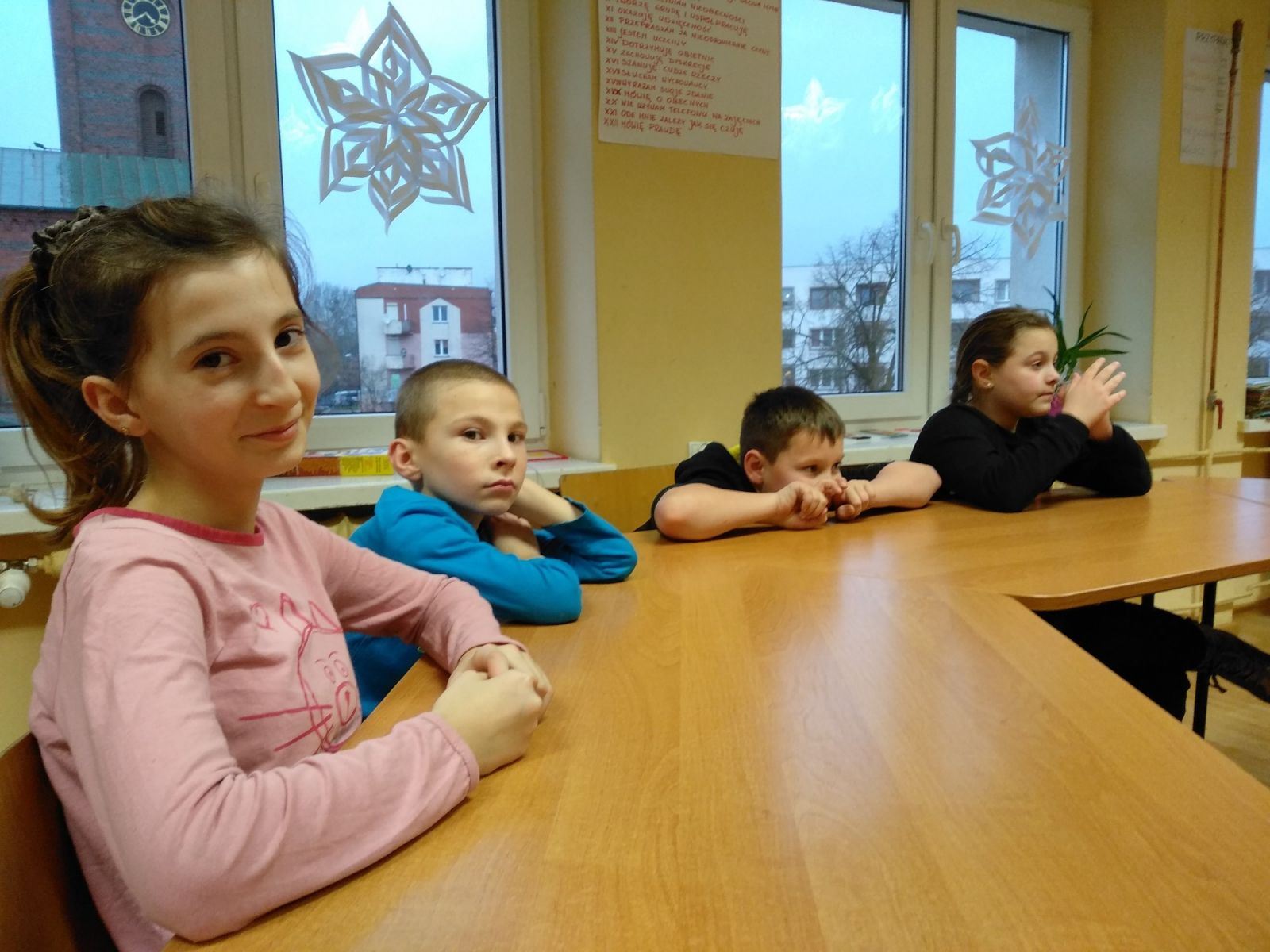 Powiększ zdjęcie. Dzieci siedzą w ławkach