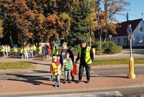 Powiększ  zdjęcie. Strażnik miejski przeprowadza dzieci przez pasy