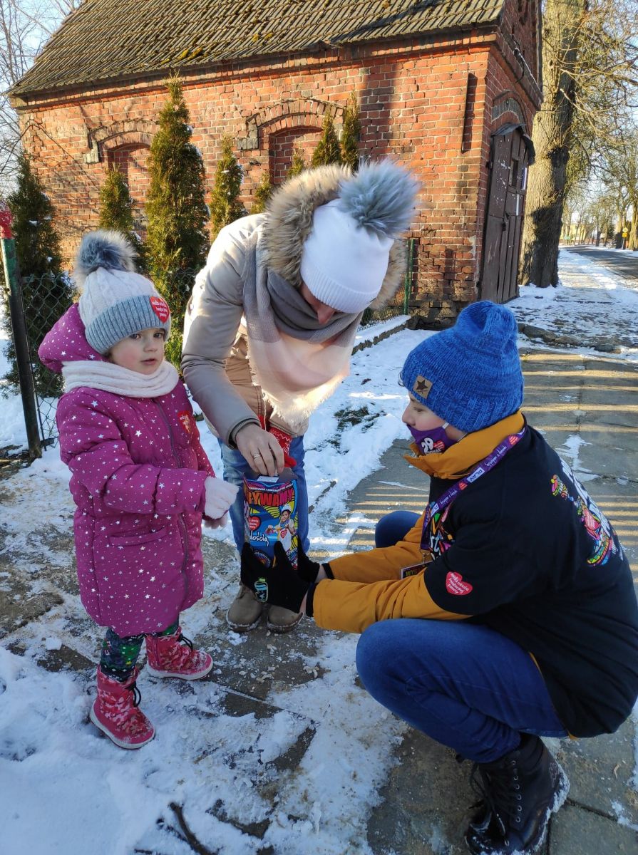 Powiększ zdjęcie. Małe dziecko wrzuca pieniadze do puszki WOŚP