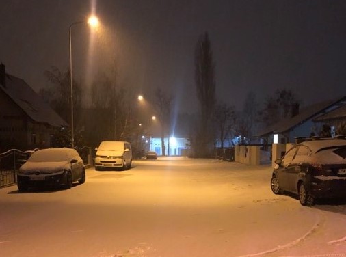 Powiększ zdjęcie. Zaśnieżona droga, samochody, zmrok, świecące lampy