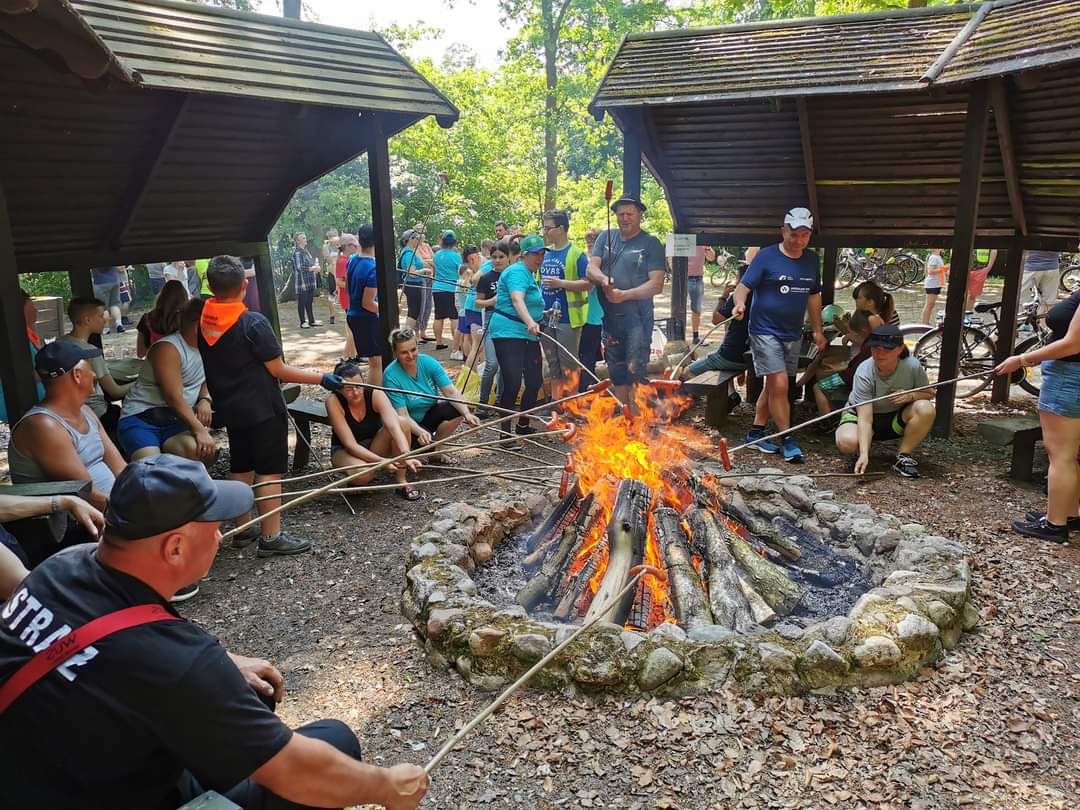 Uczestnicy rajdu w kręgu ogniska smażą kiełbaski