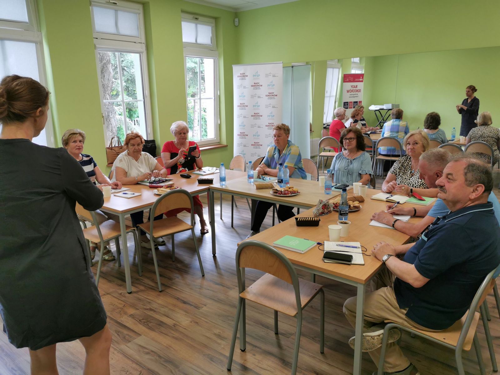 Powiększ zdjęcie. Seniorzy siedzą w ławce. 