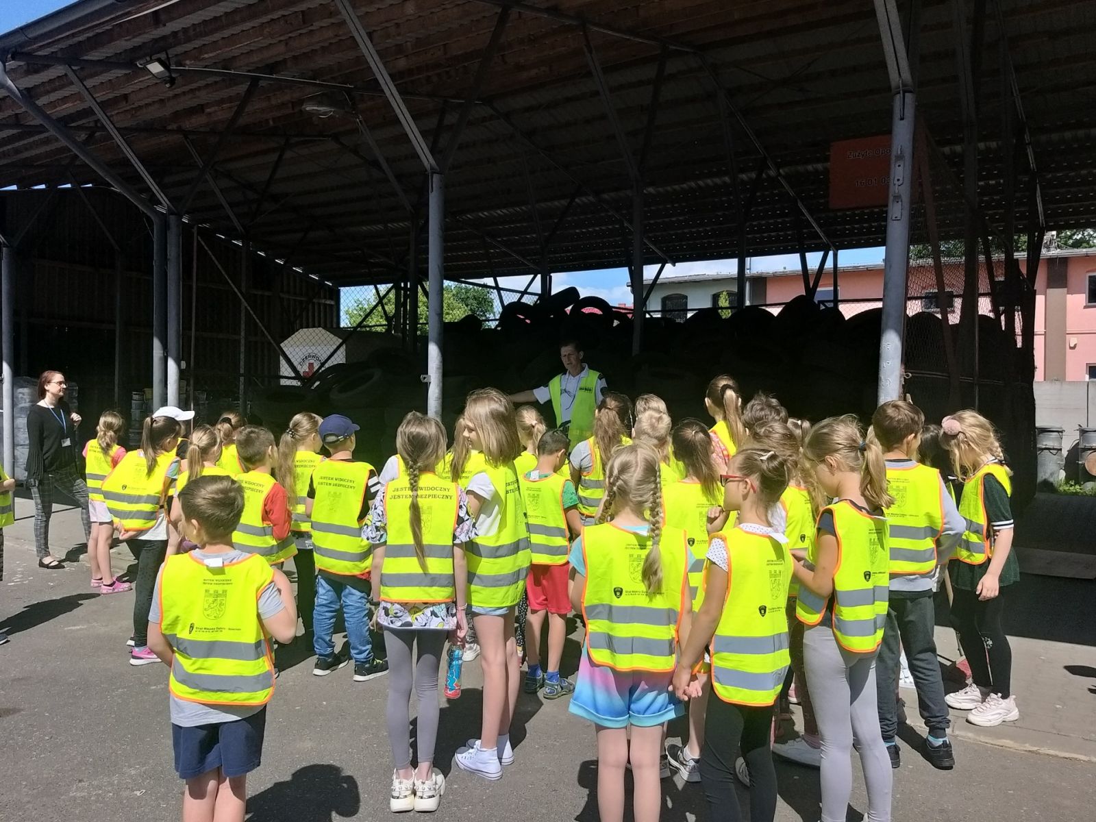 Powiększ zdjęcie. Na zewnątrz Dzieci w kamizelkach stoją, komendant opowiada