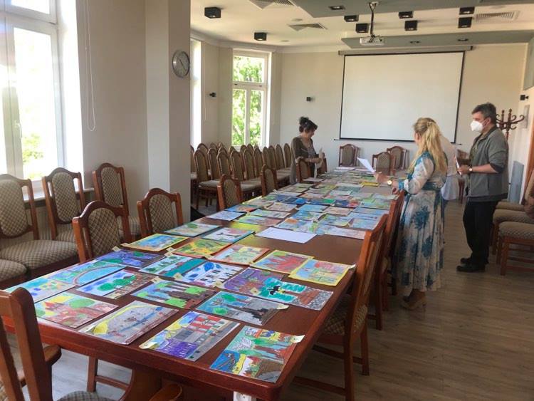 Prace plastyczne rozłożone na stole. komisja przygląda się pracom