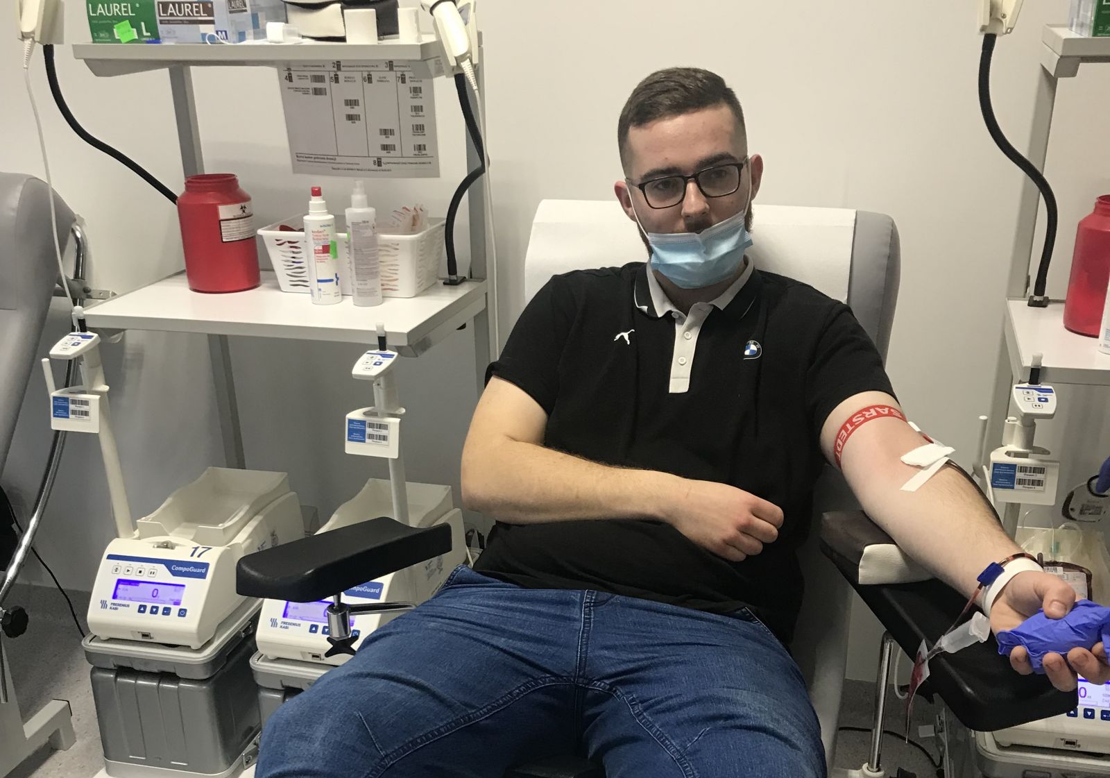 Chłopak w maseczce leży na fotelu oddaje krew