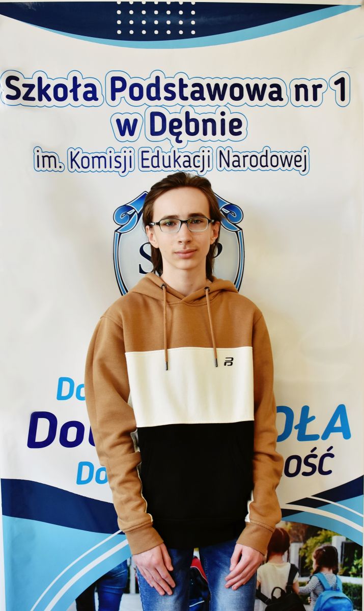 Powiększ zdjęcie. Marcin Matłacki, w tle baner szkoły