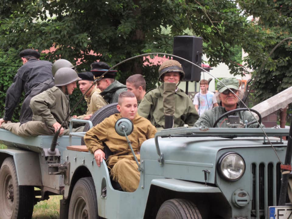 Młodzież w munurach wojskowych, jedzie w łaziku wojskowym