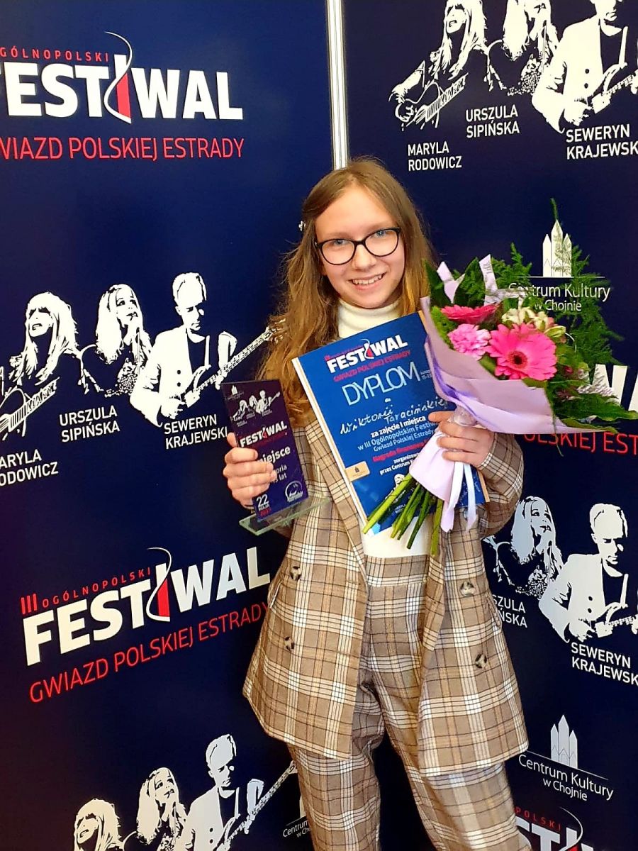 Powiększ zdjęcie. Uśmiechnięta Wiktoria Taracińska trzyma dyplom i bukiet w dłoni