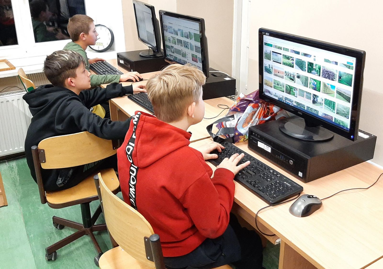 Trzech chłopców siedzi przed monitorami