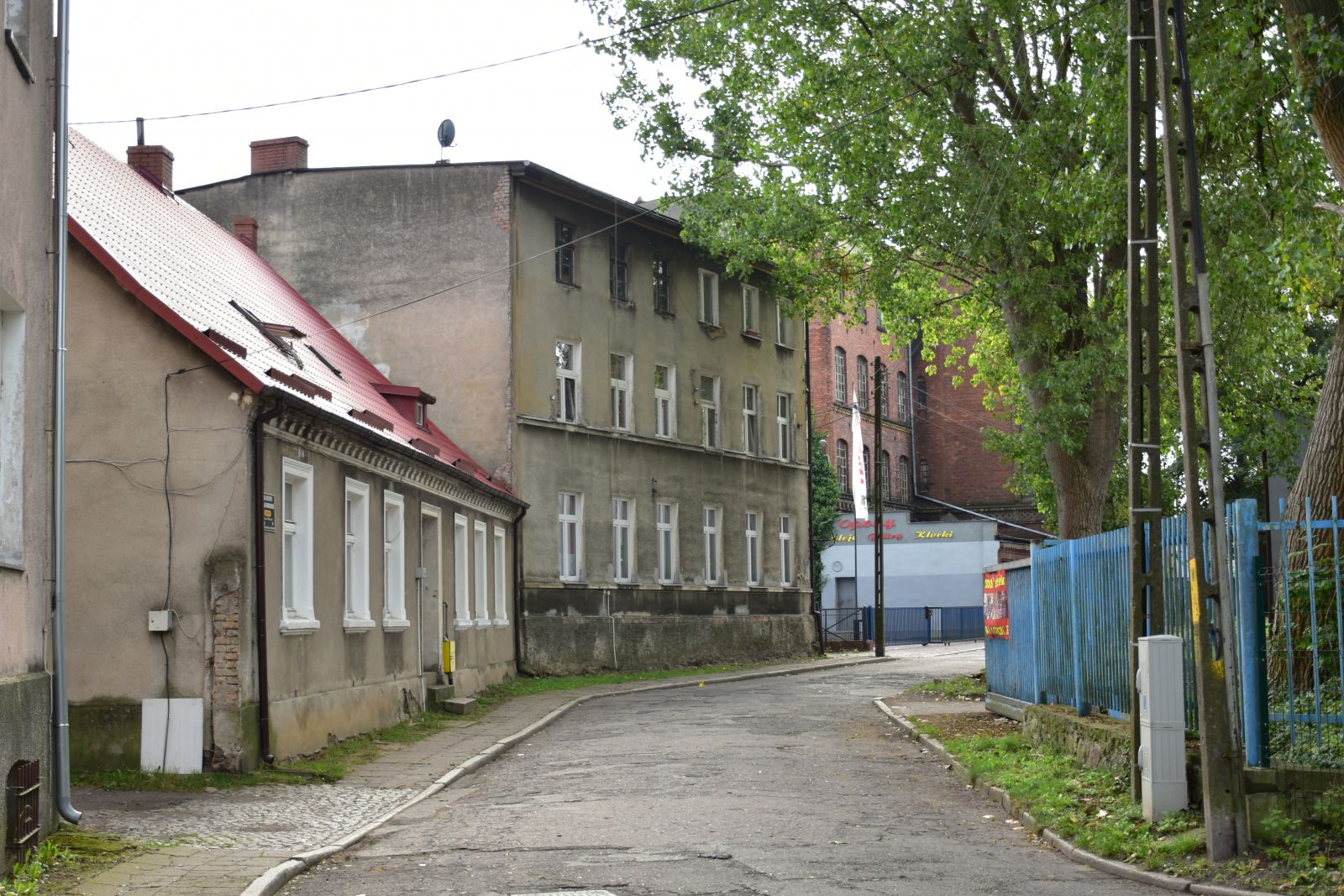 Powieksz zdjęcie. Zniszczona droga, chodniki, stare budynki