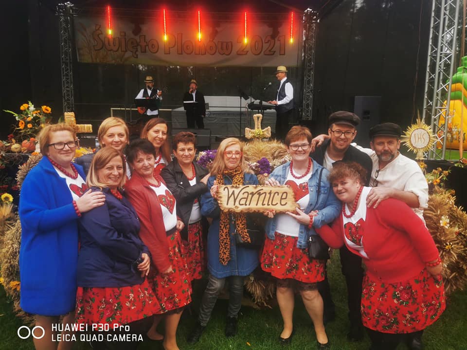 Zadowoleni mieszkańcy Warnic, w tle wieniec, scena 