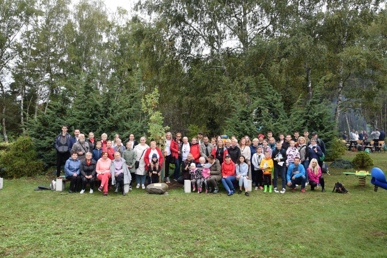 Wspólne zdjęcie uczestników, w tle drzewa, zielona trawa