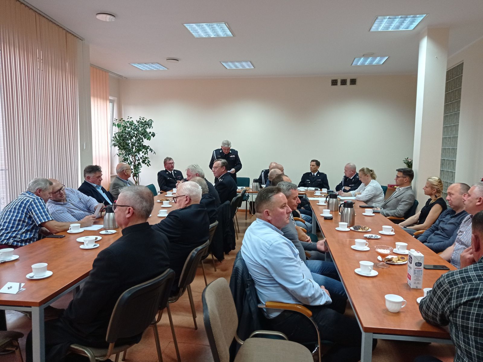 Powiększ zdjęcie. Ludzie siedzą przy stołach 