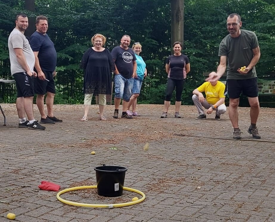 8 osób dorosłych na świeżym powietrzu, jeden rzuca do celu - wiaderka