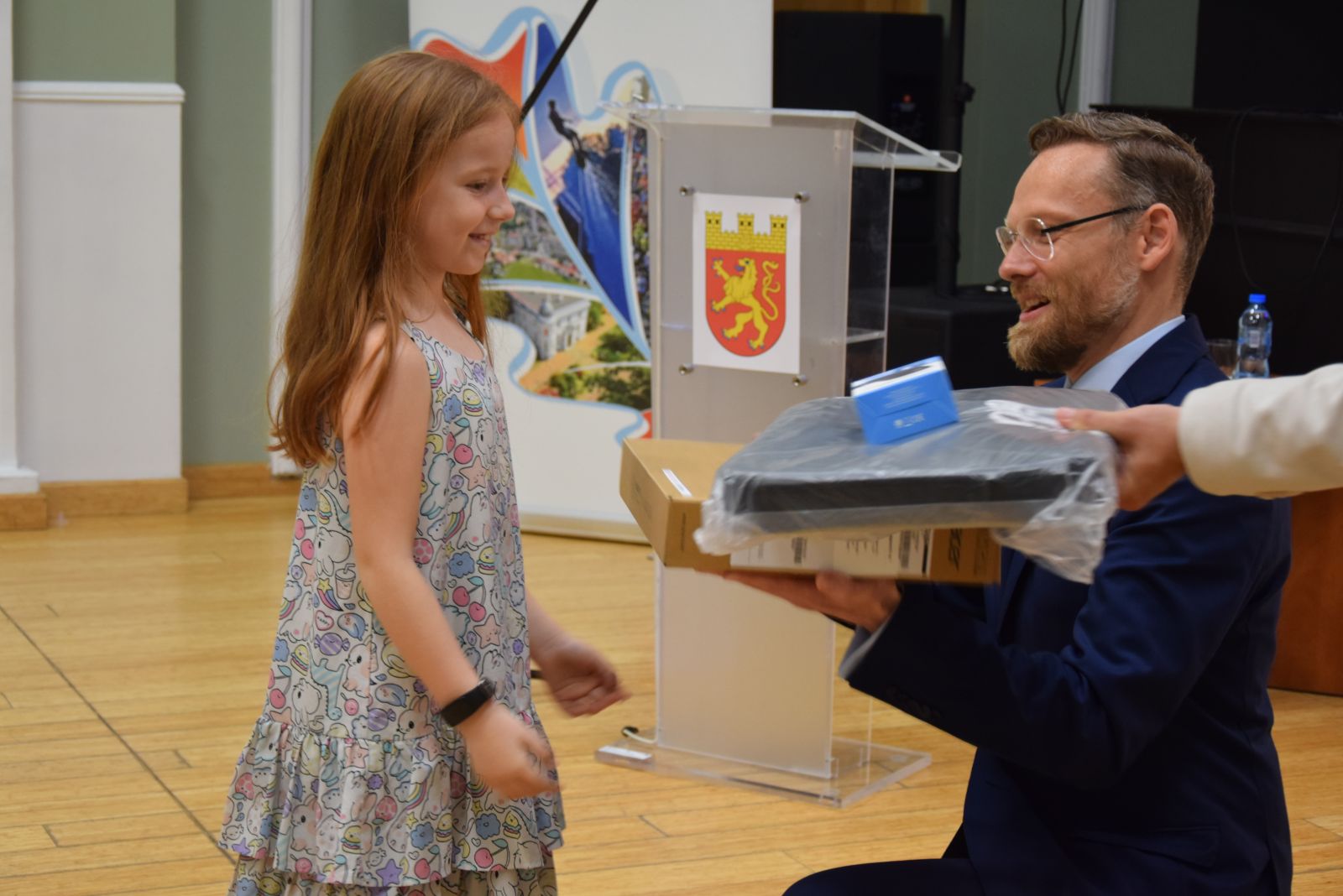 Powiększ zdjęcie. Wojewoda wręcza komputer małej dziewczynce