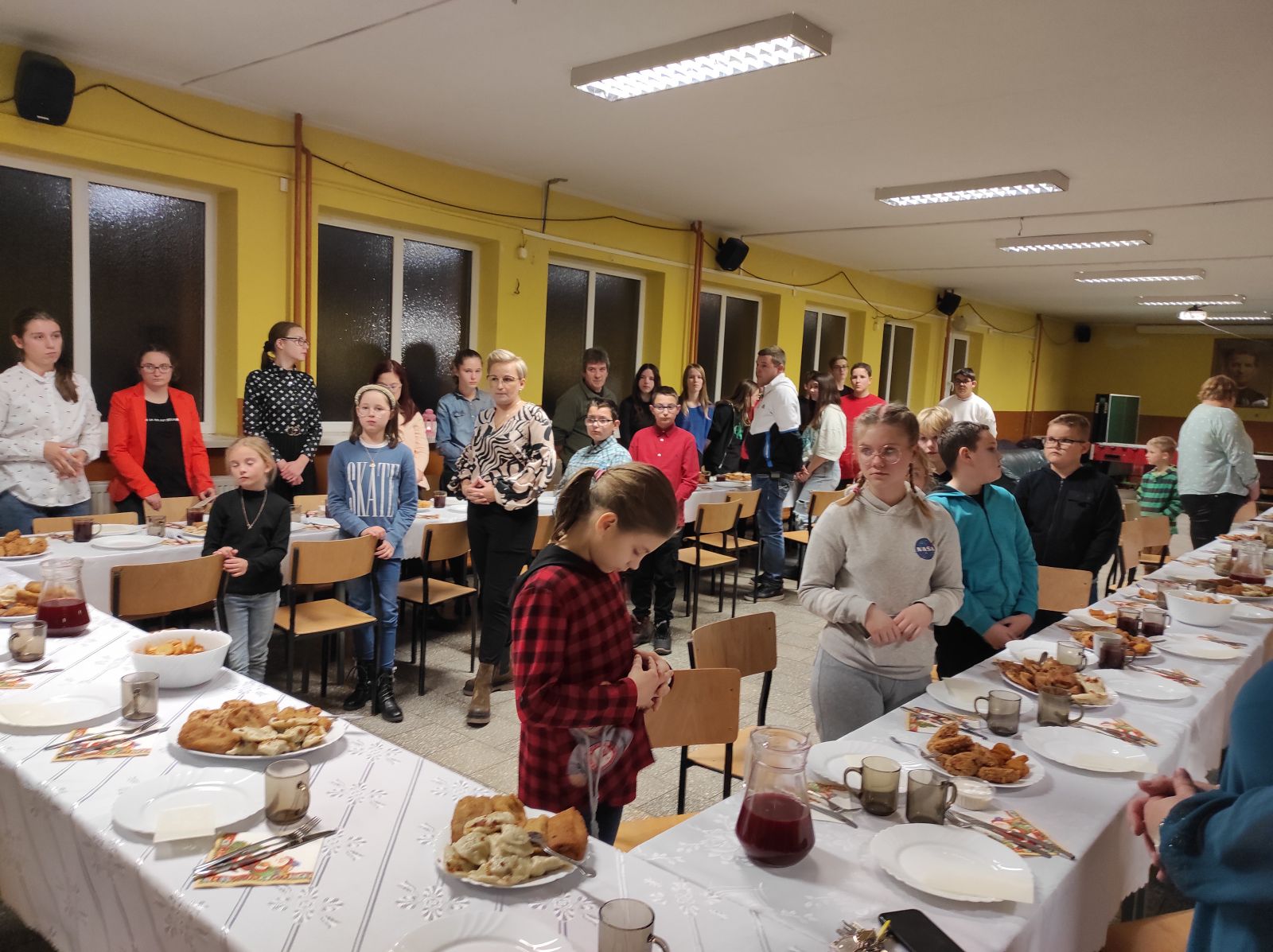 Dzieci stoją przy stołach świątecznie nakrytych 