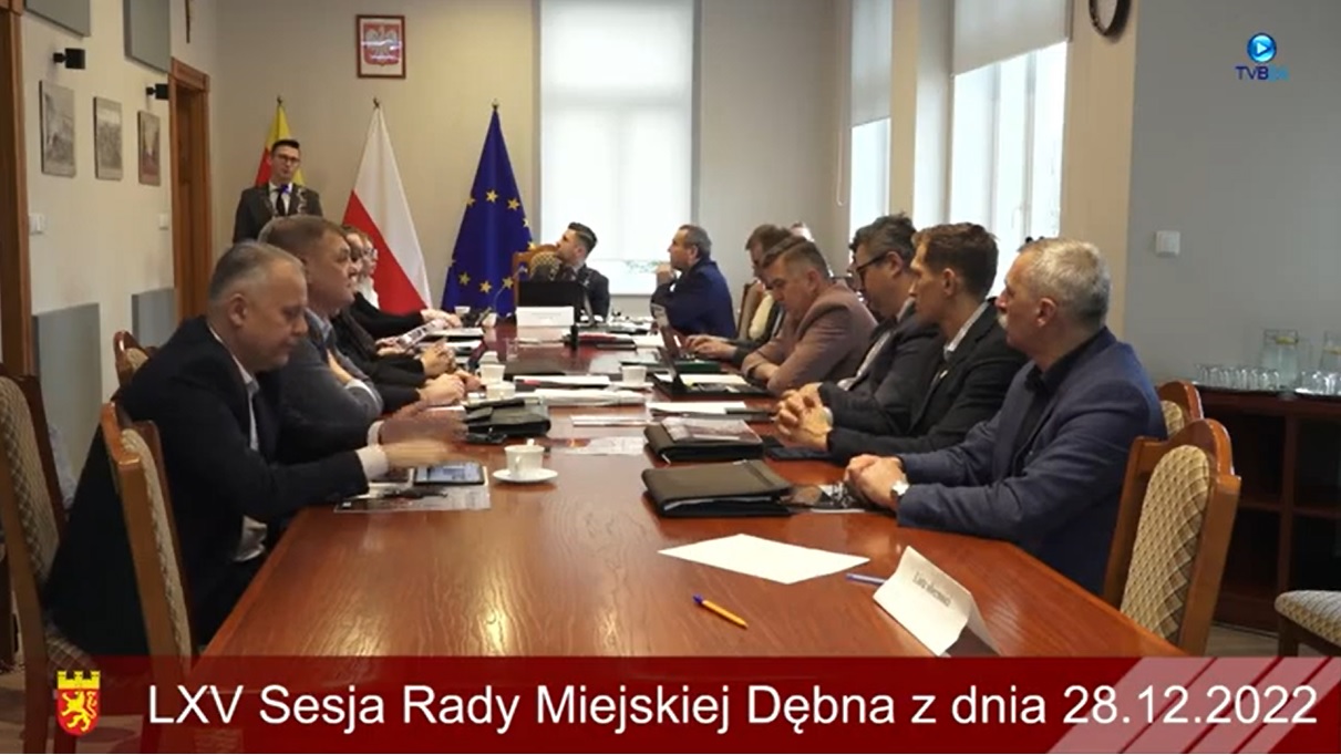 Powiększ zdjęcie. Radni siedzą przy stole podczas sesji, burmistrz stoi przy mównicy