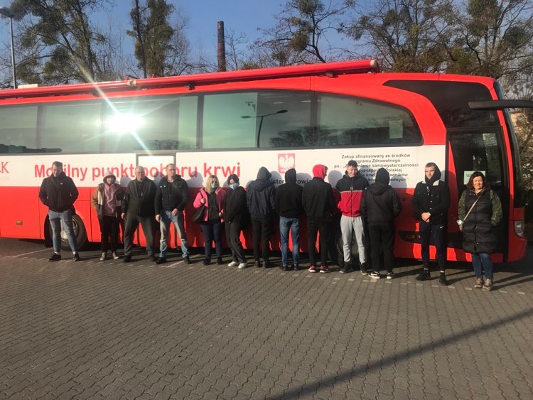 Grupa uczniów stoi przed kwiobusem 