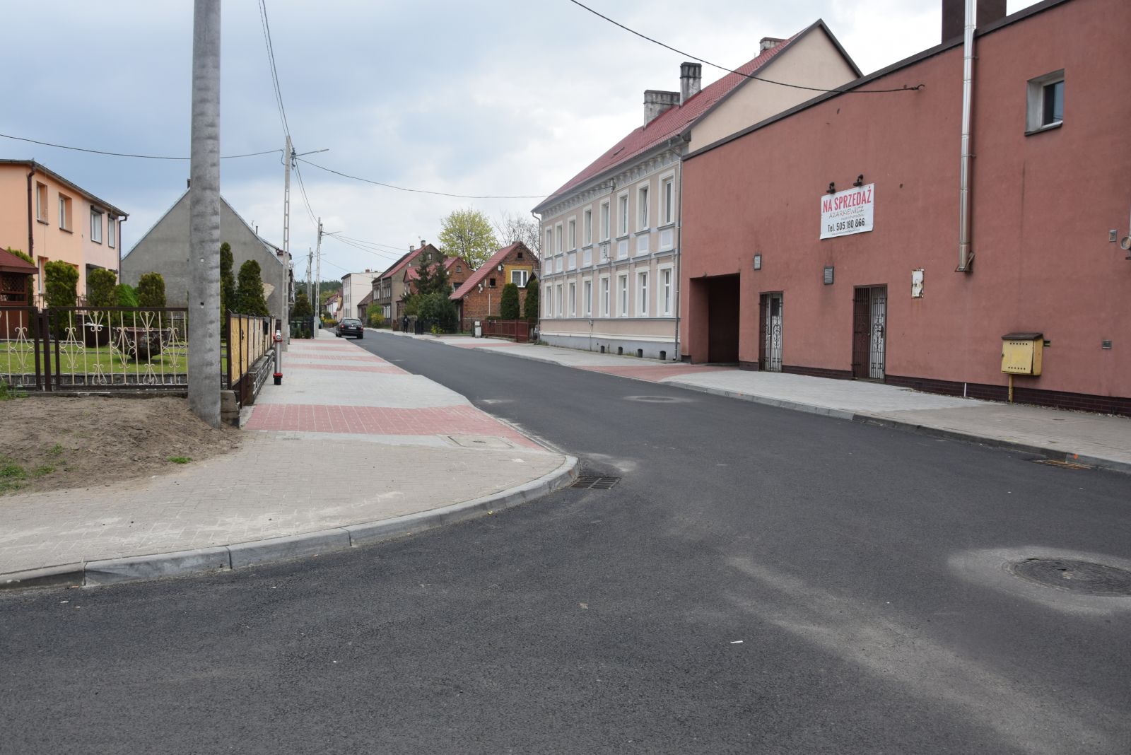 Droga asfaltowa, słupy, budynki, niebo