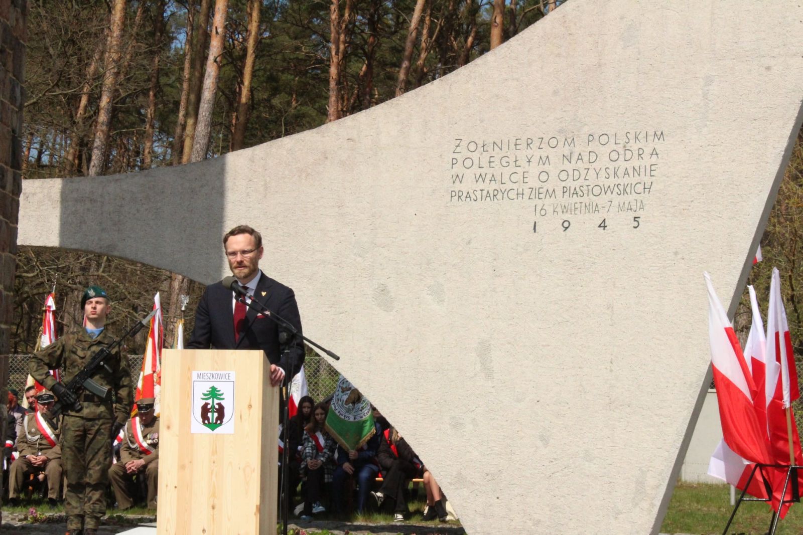 Powiększ zdjecie. Wojewoda przemawia, w tle pomnik 