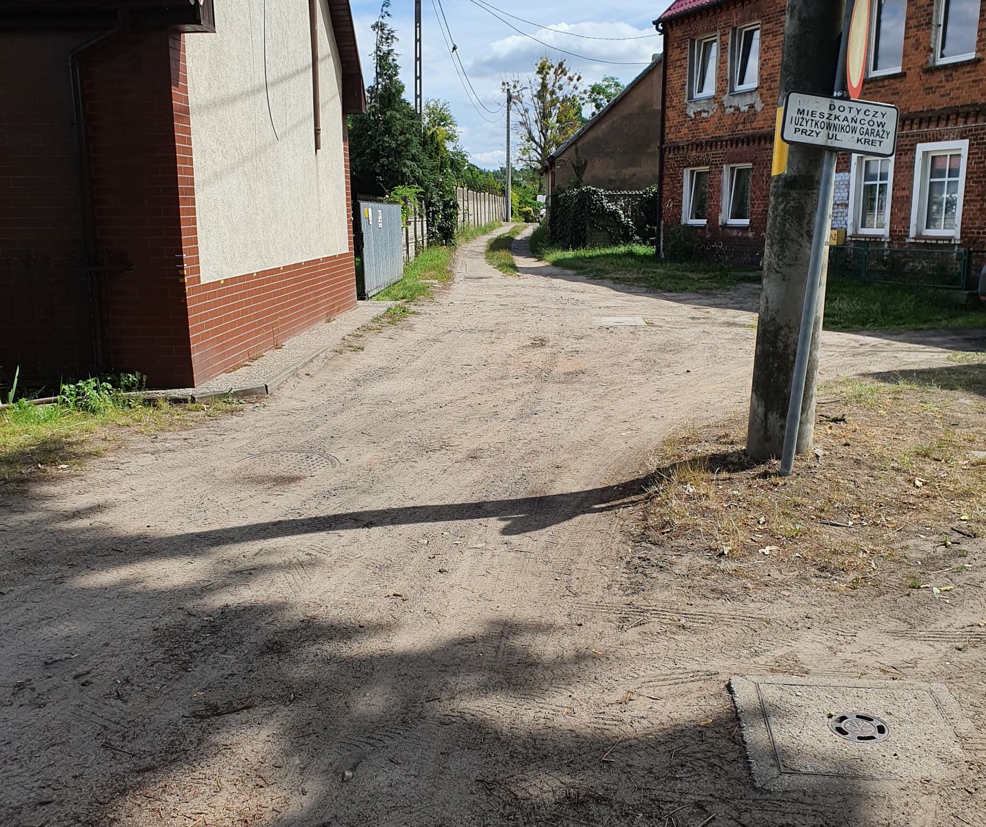 Powiększ zdjęcie. Droga nie utwardzona miedzy budynkami