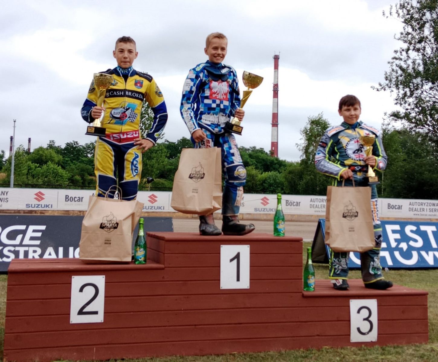 Powiększ zdjęcie. Trzech zawodników na podium. Pierwszy od lewej Kewin