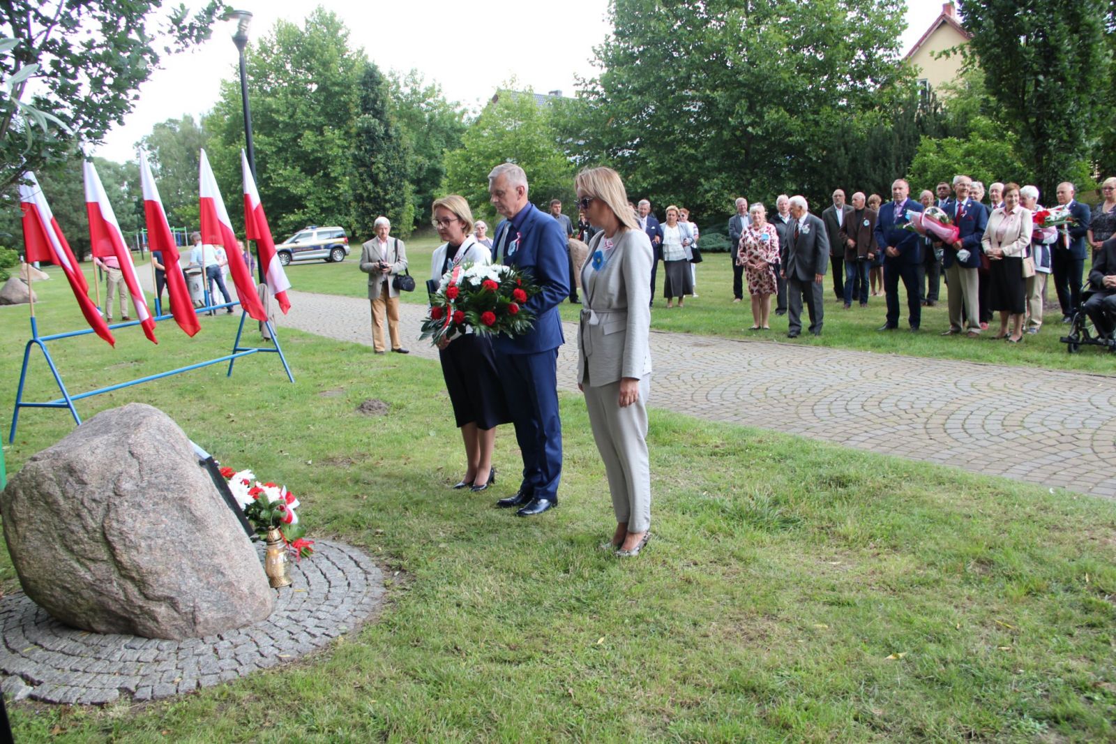 Powiększ zdjęcie. delegacja samorządu składa kwiaty przed głazem 