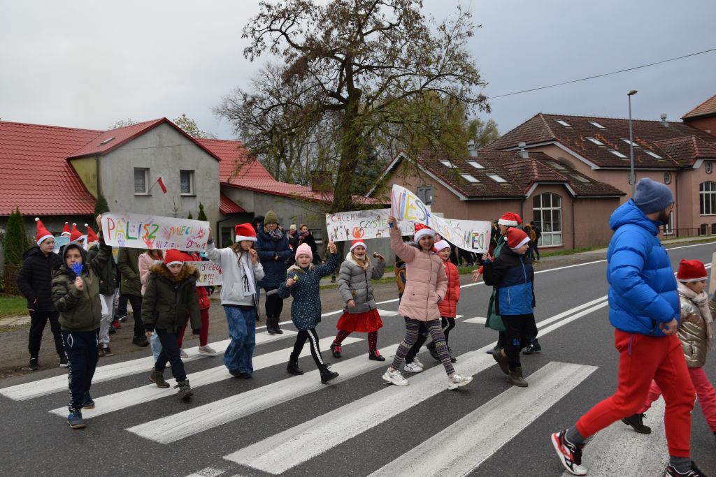Dzieci idą przez pasy z transparentami
