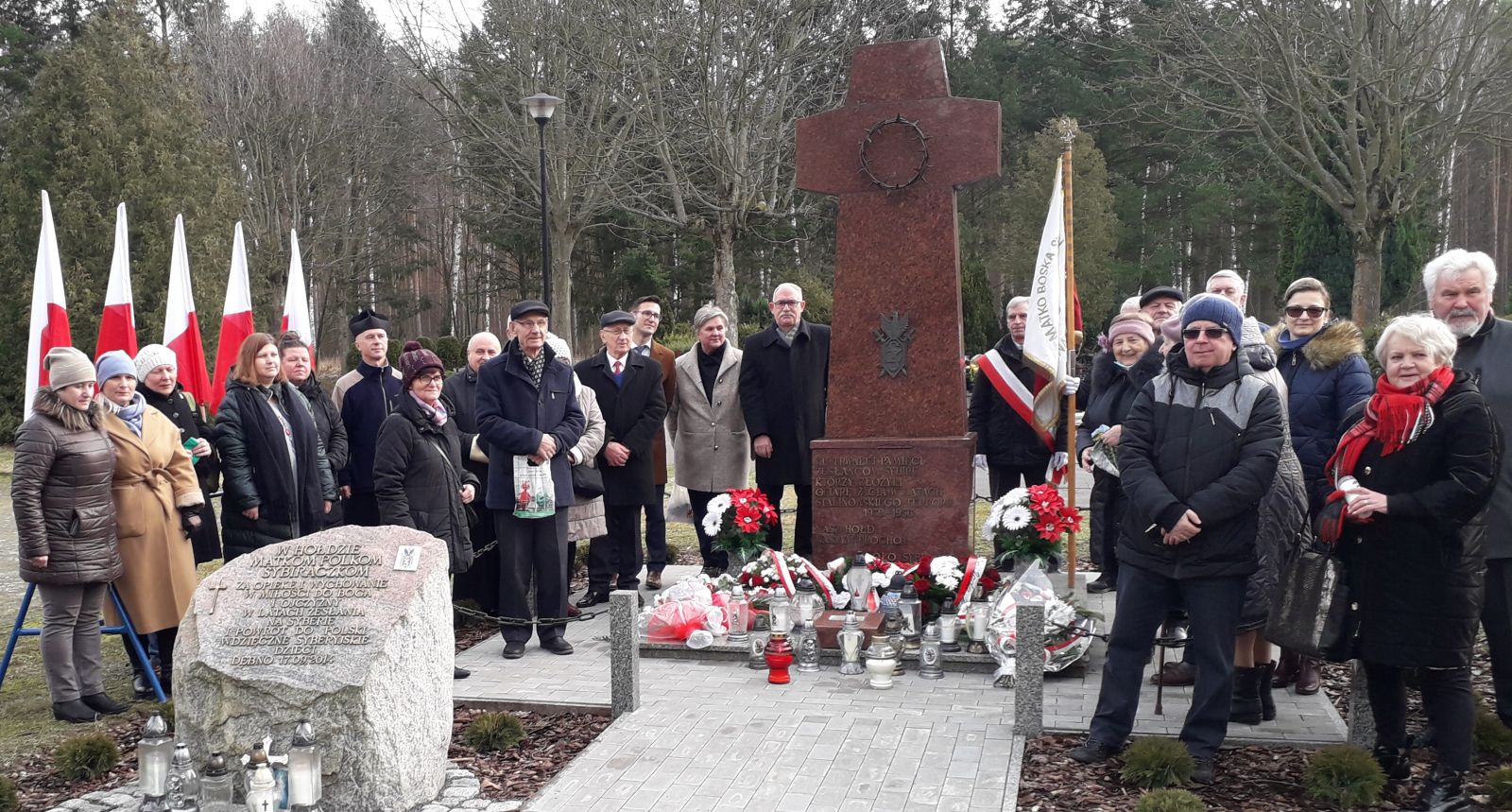 Grupowe zdjęcie uczestników uroczystości przed pomnikiem 