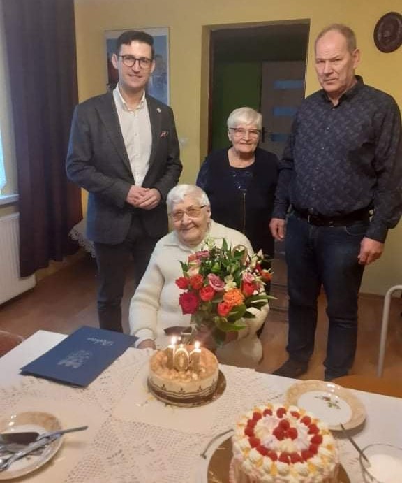 Powiększ zdjęcie.Od lewej: burmistrz, córka jubilatki, sołtys, przed nimi siedzi pani Kazimiera