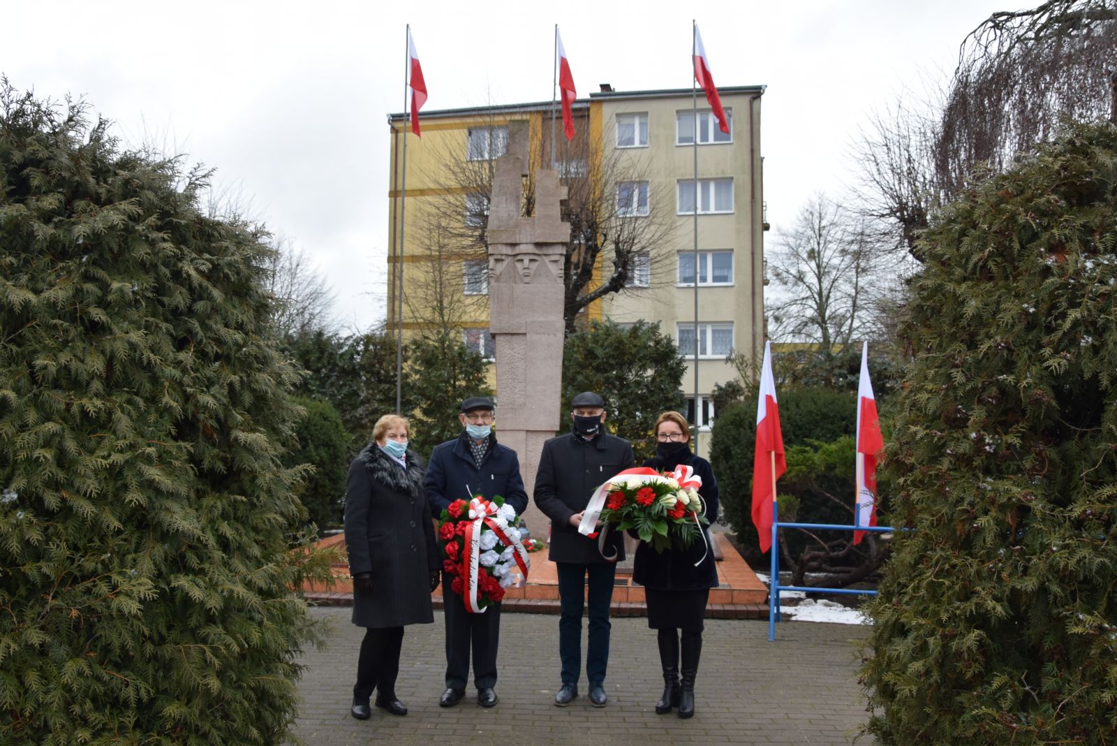 Powiększ zdjęcie. Czterosobowa delegacja z kwiatami