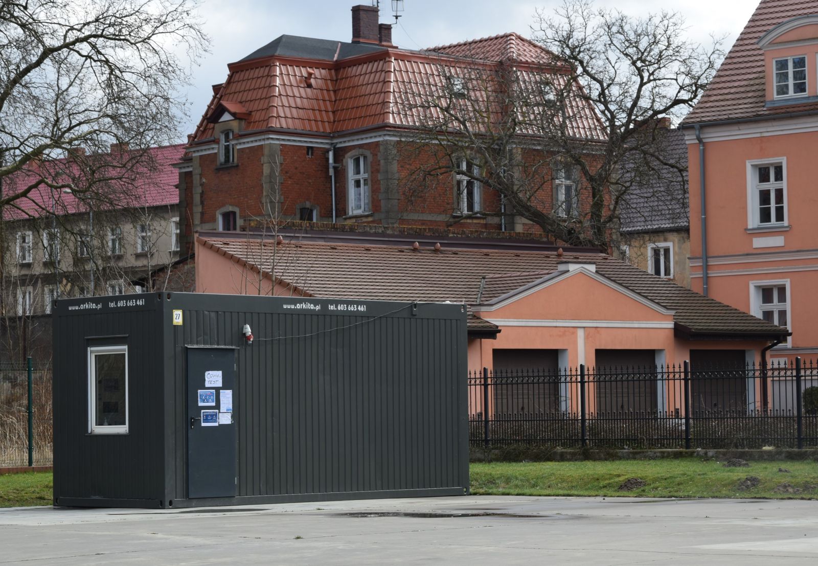 Kontener na placu, w którym wykonywane są testy, w tle budynki mieszkalne