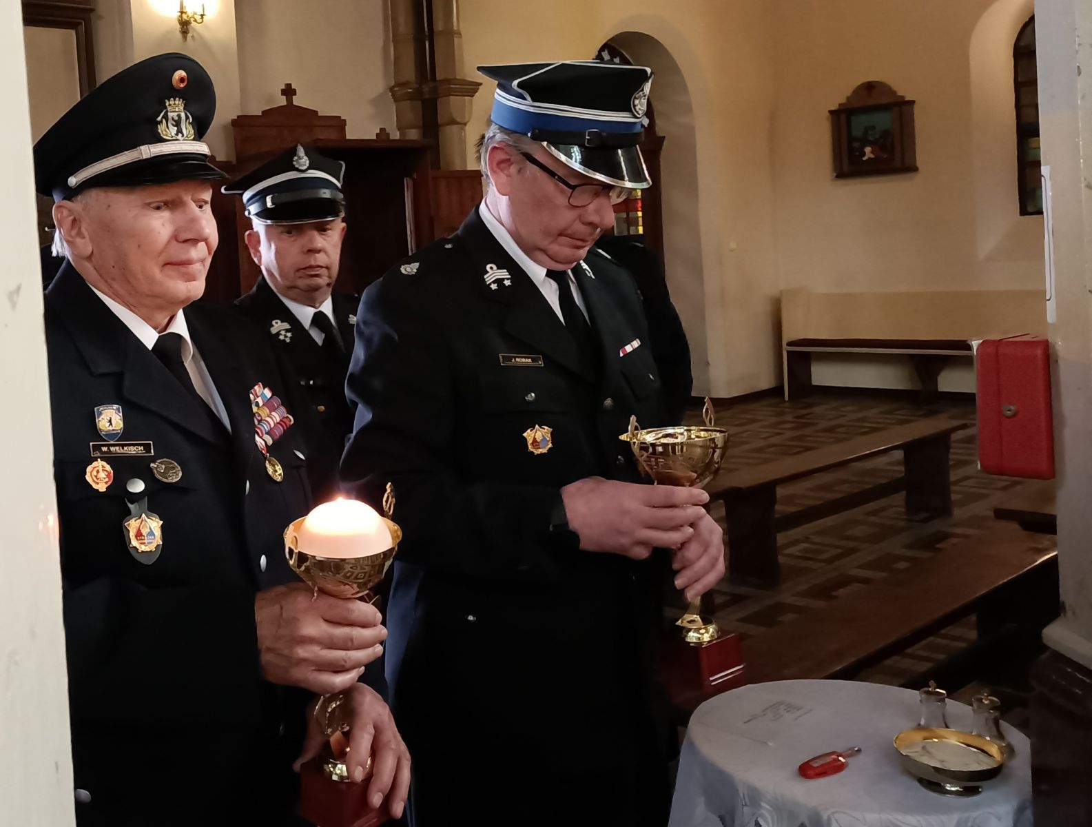 Powiększ zdjęcie. Strażacy w mundurach niosą dary
