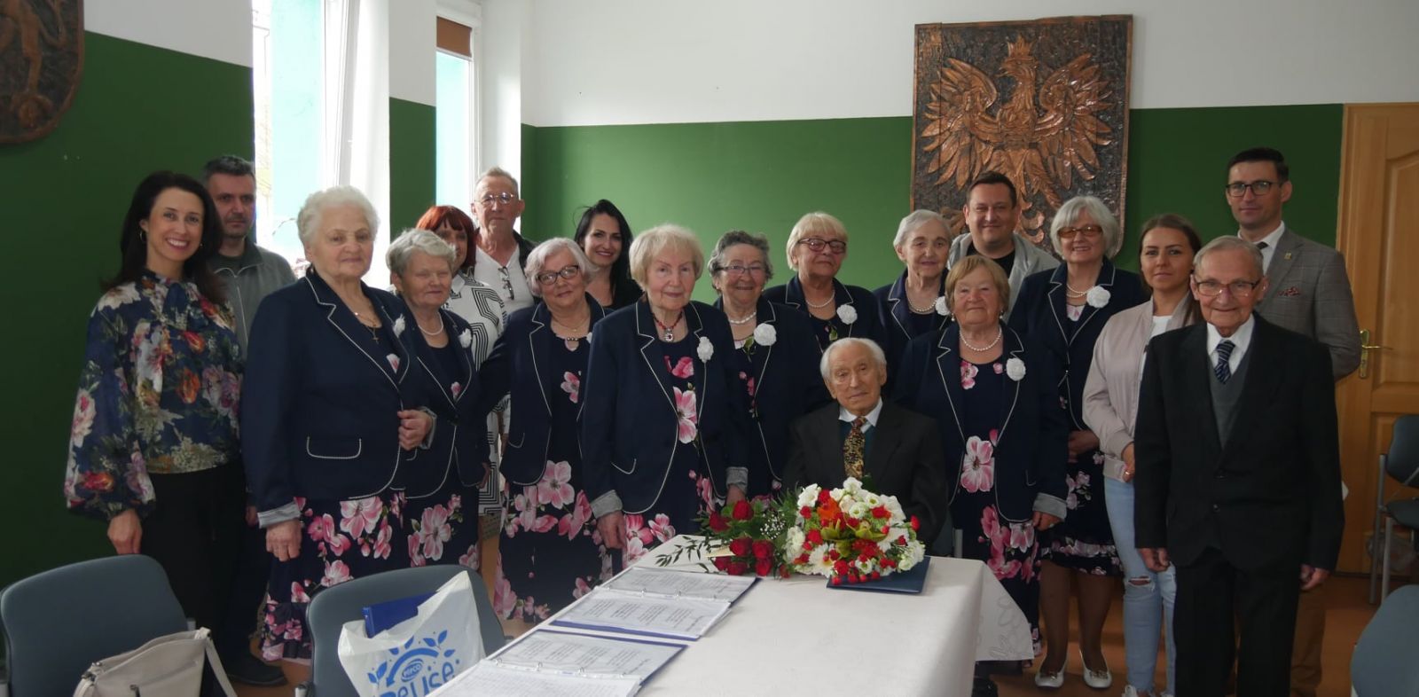 W środku siedzi Jan Zaremba, wokół niego członkowie Zespołu, pracownicy DOK i burmistrz