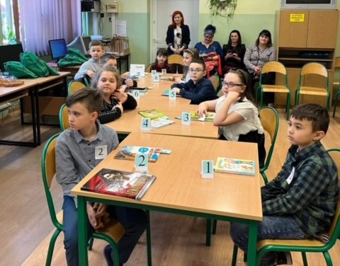 Dzieci siedzą w ławkach