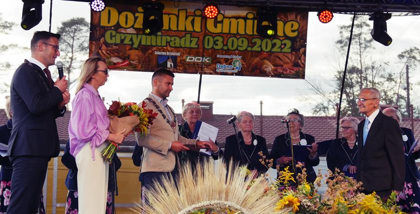 Burmistrz i przewodniczacy rady na scenie wreczają medal Tadeuszowi Pencakowi