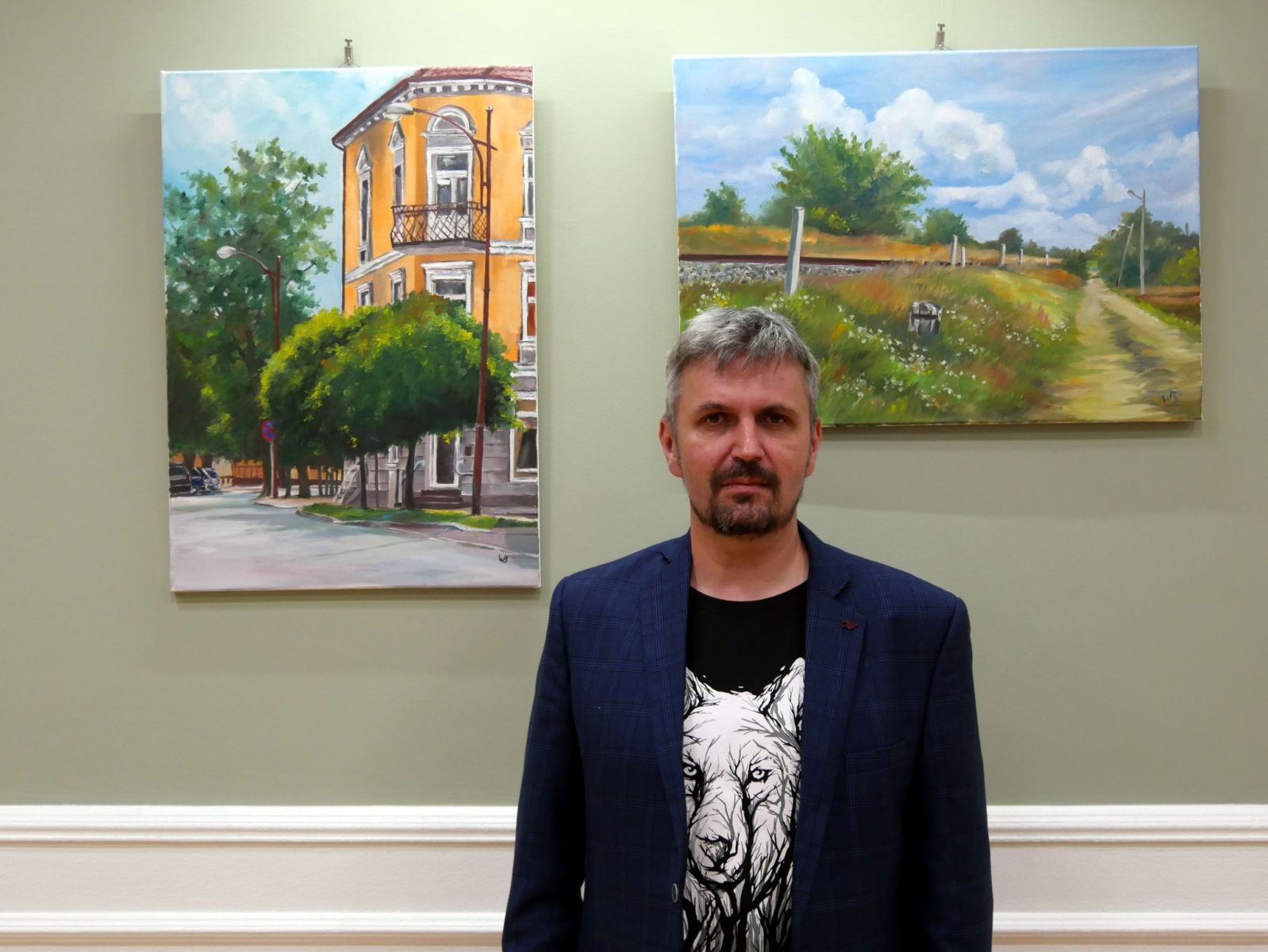 Artysta z Dębna na tle swoich obrazów