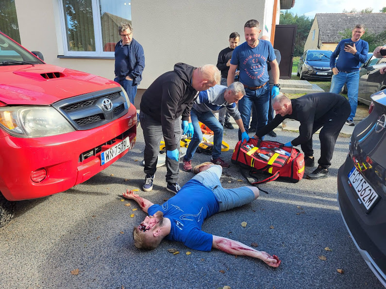 Leży poszkodowany,, uczestnicy szkoelnia udzielają pierwszej pomocy