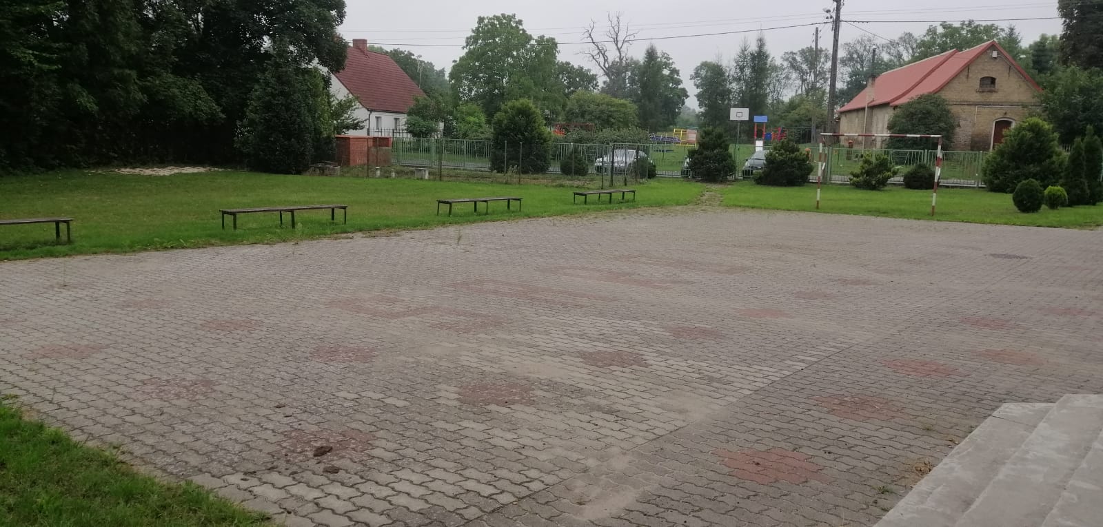 Powiększ zdjęcie. Plac wyłożony betonową kostką, dokoła ławki