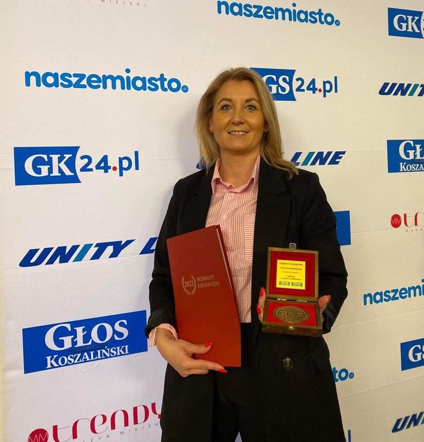 Powiększ zdjęcie. Wyróżniona nauczycielka trzyma pamiatkowy medal i list 